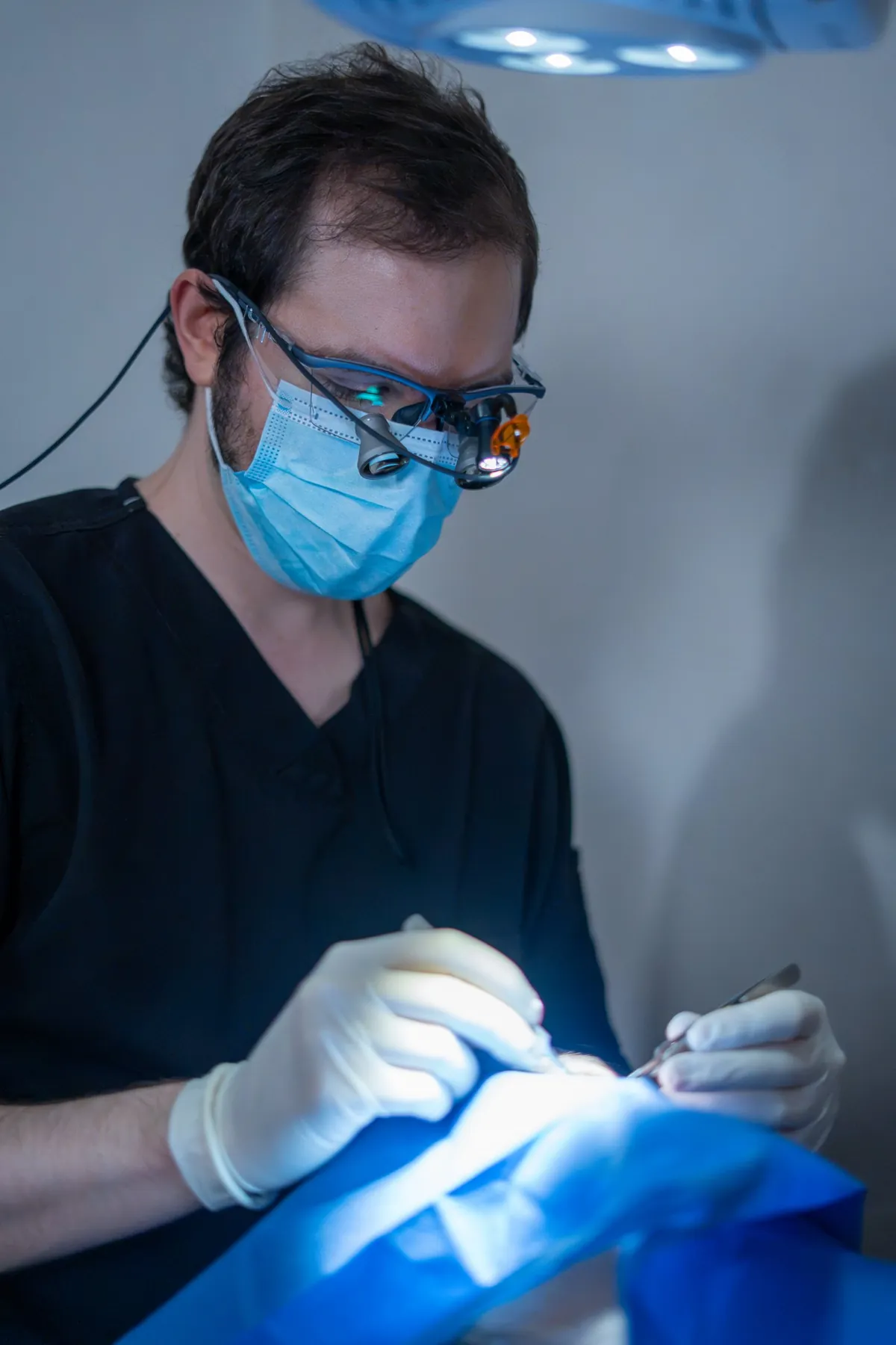 Dr. Sebastián Diener, oftalmólogo oculoplástico, realizando cirugía menor de párpado con lupas quirúrgicas en CDMX
